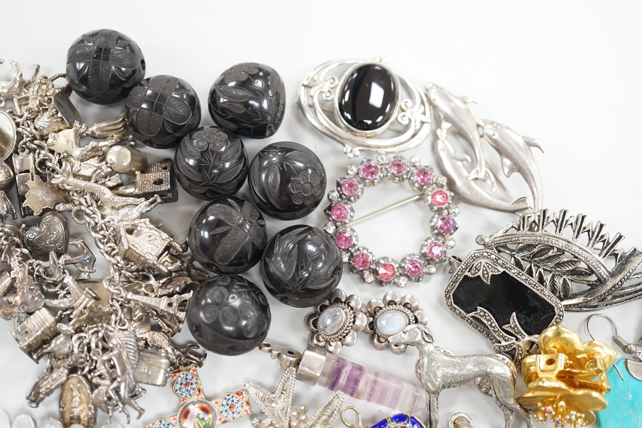 A silver charm bracelet hung with fifty assorted charms and a group of assorted jewellery including enamelled locket, Victorian agate fob seal carved with a bird, scarab pendant, coloured paste set brooch, 925 triple dol